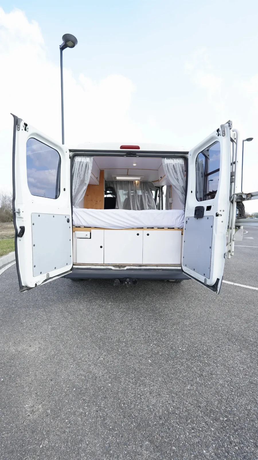 Rear doors open on the Fiat Ducato campervan, showing the bed platform