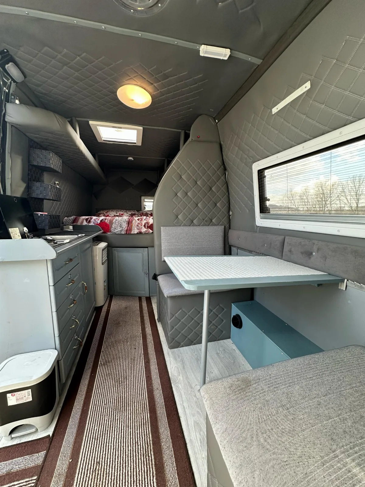 Inside the Mercedes-Benz Sprinter campervan, with the kitchen, table and bed