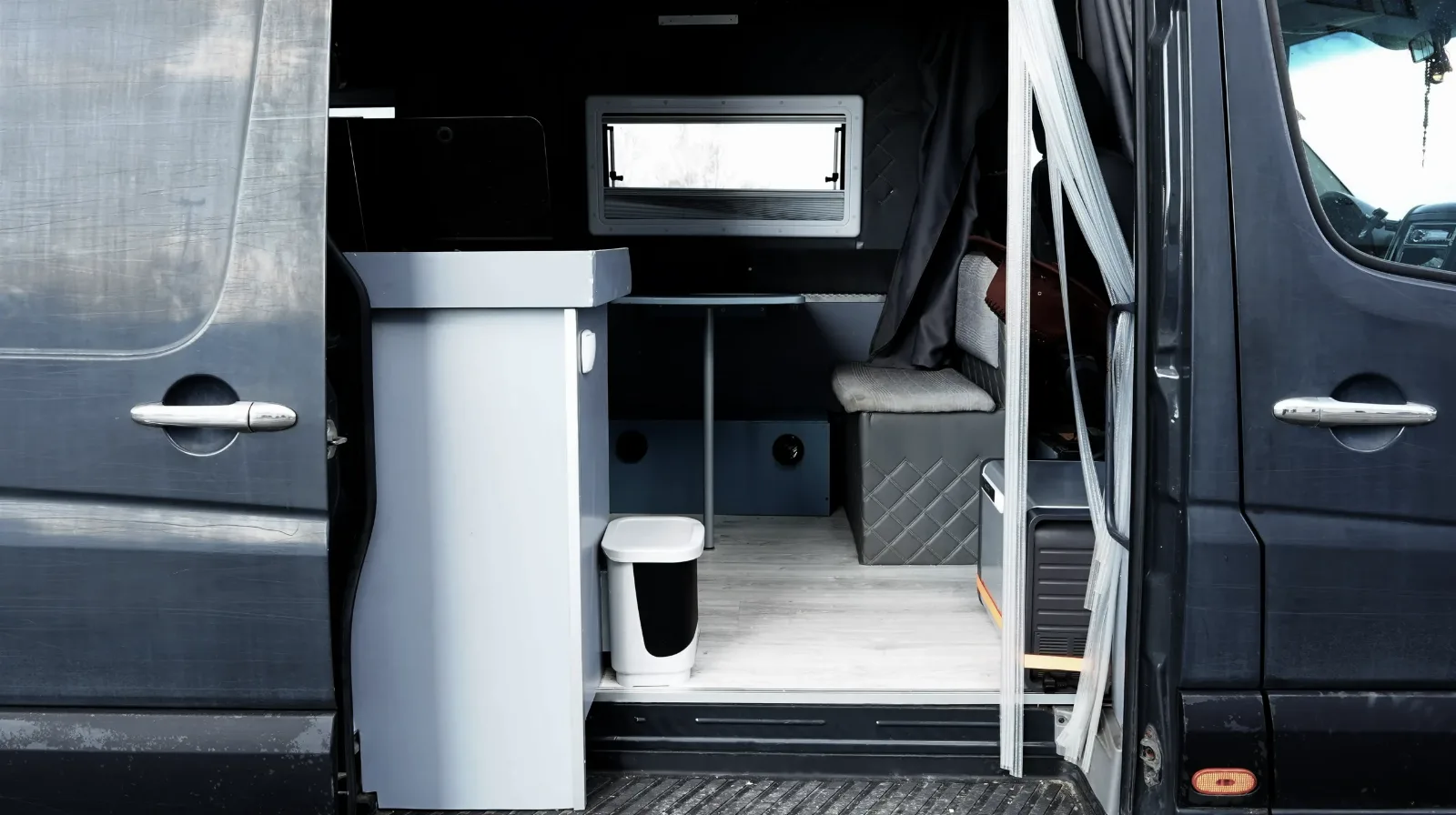 Rear doors open on the Mercedes-Benz Sprinter campervan, showing the washroom unit