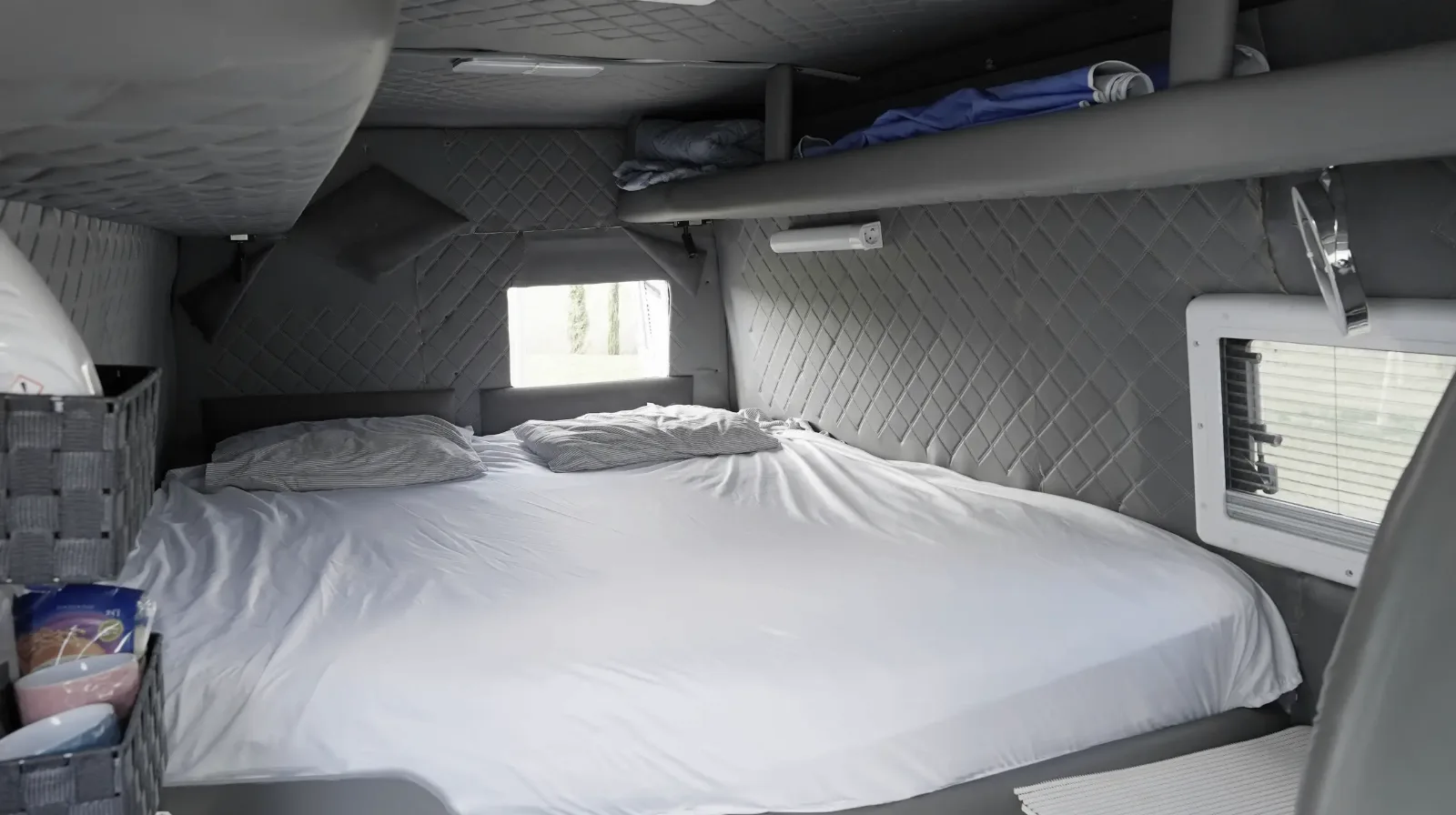 Rear bed made up in the Mercedes-Benz Sprinter campervan, with quilted grey lining