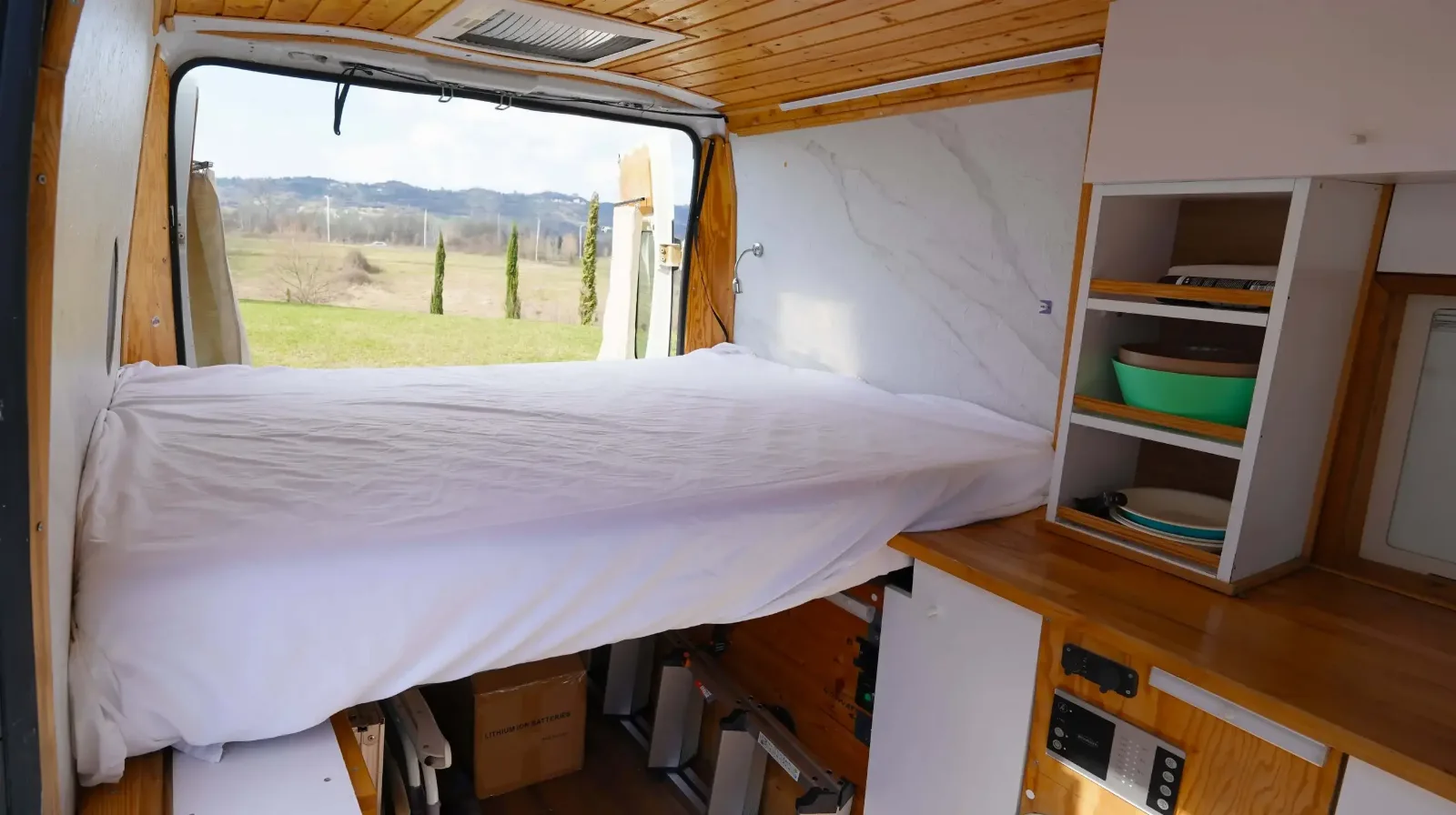 Bed and shelving in the Peugeot Boxer campervan, countryside through the window