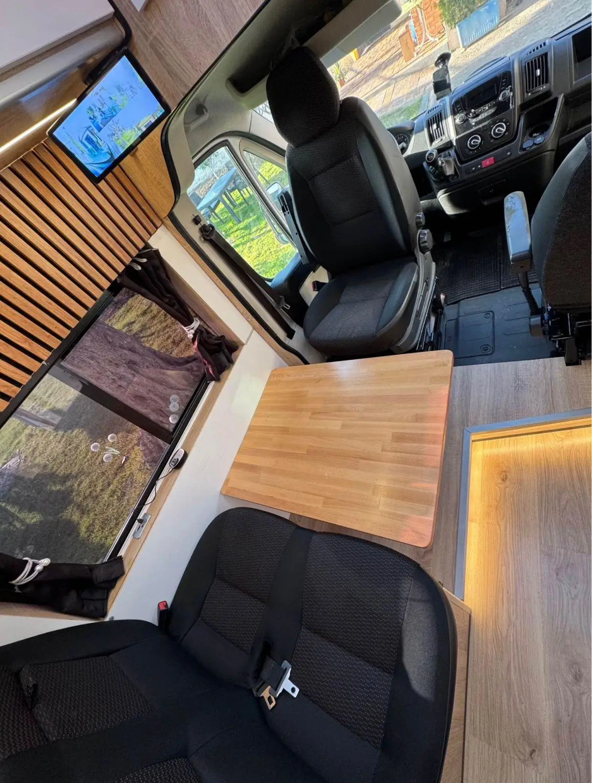Dinette with a wooden table and swivelled cab seats in the Peugeot Boxer campervan