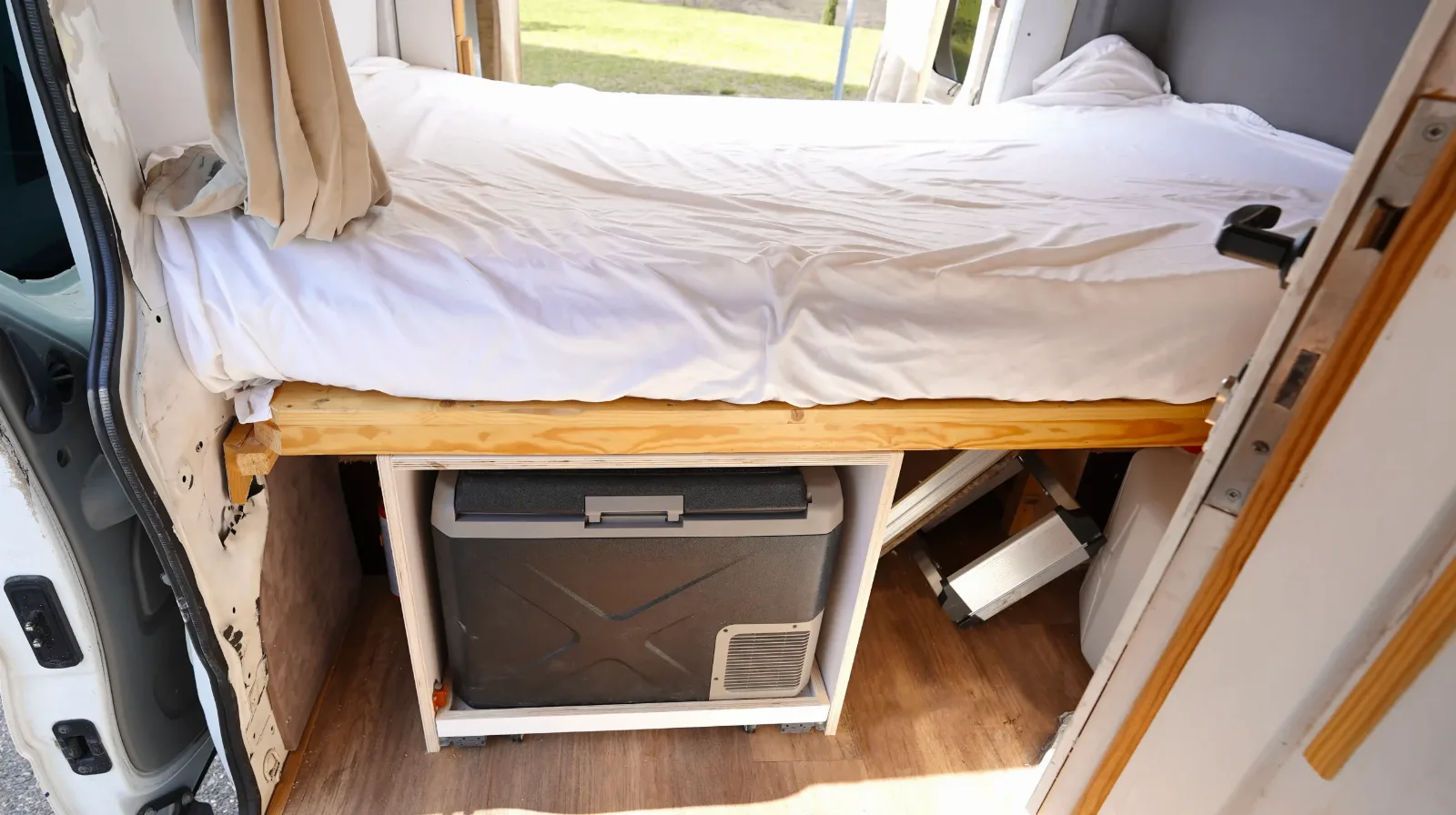 Bed with storage and a fridge underneath in the Renault Trafic campervan