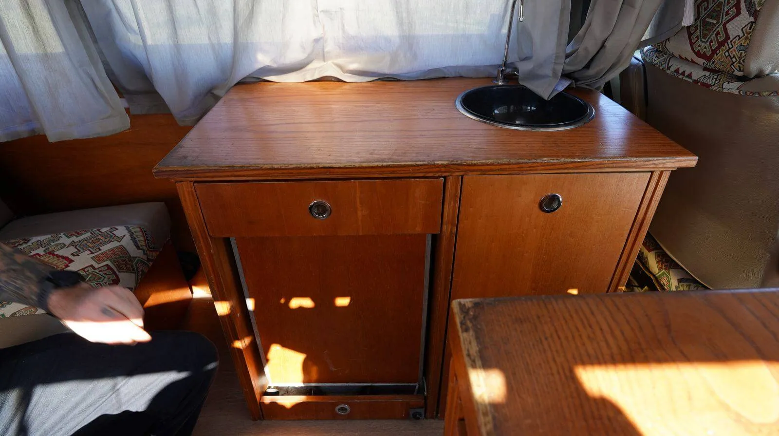 Wooden cabinet with a sink and swing-out table in the Volkswagen Westfalia campervan